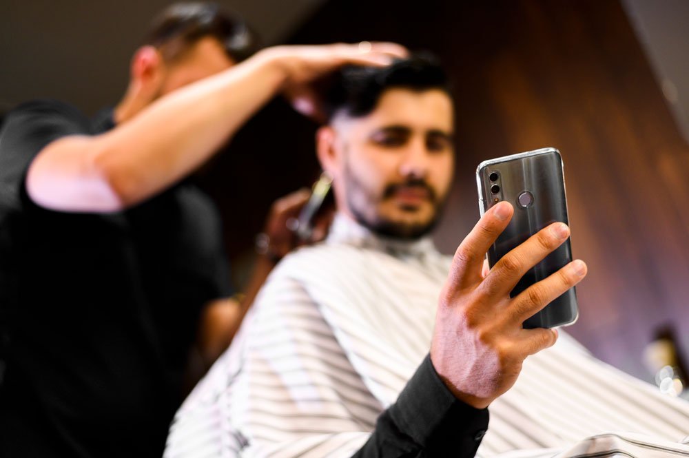 low angle costumer barber shop looking phone